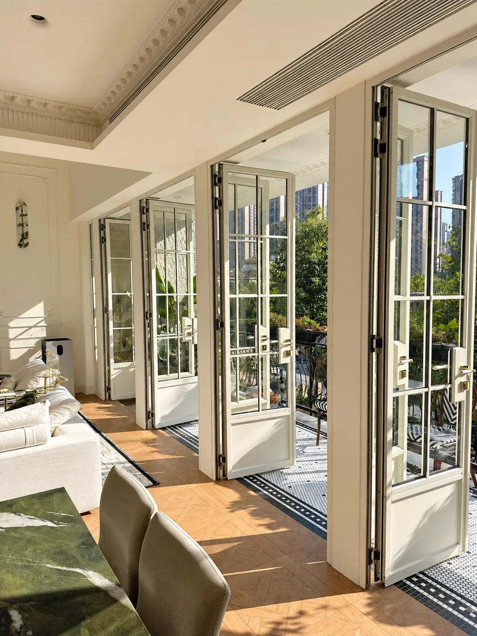 Cream French double doors with full-height grid glazing opening onto a sunny balcony