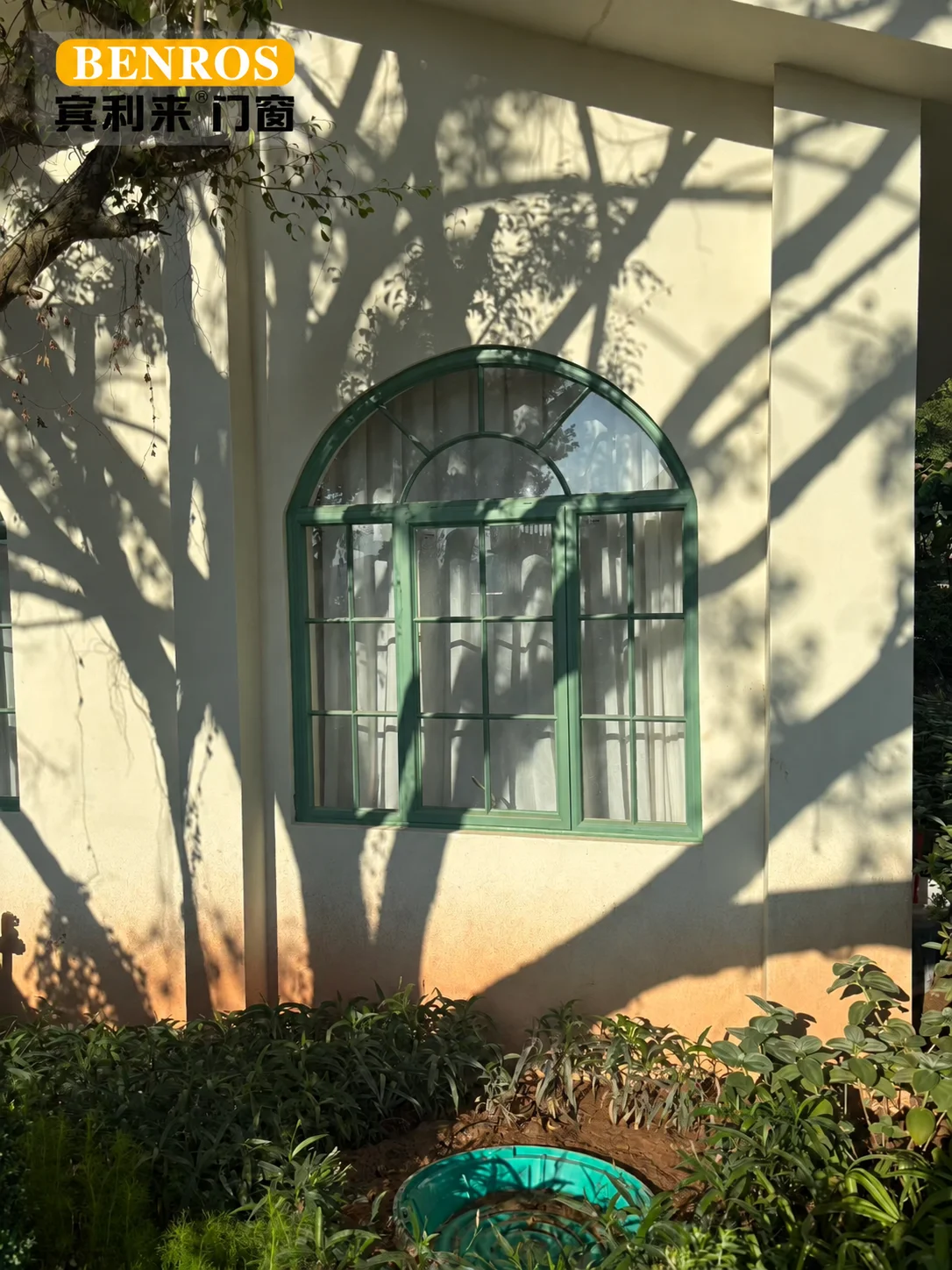 Green French-style divided-light doors and windows connecting a living room to a courtyard