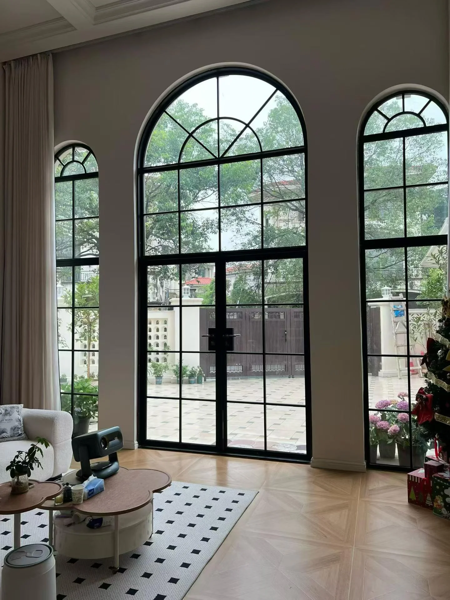 Black-framed arched aluminum French-style windows and glazed double doors in a residential living room.
